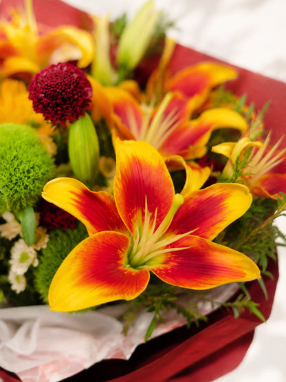 Amber Flame 特寫，鮮橙色 lilies 盛放細節，配雞冠花及綠葉，bold floral texture with vibrant sunset tones.