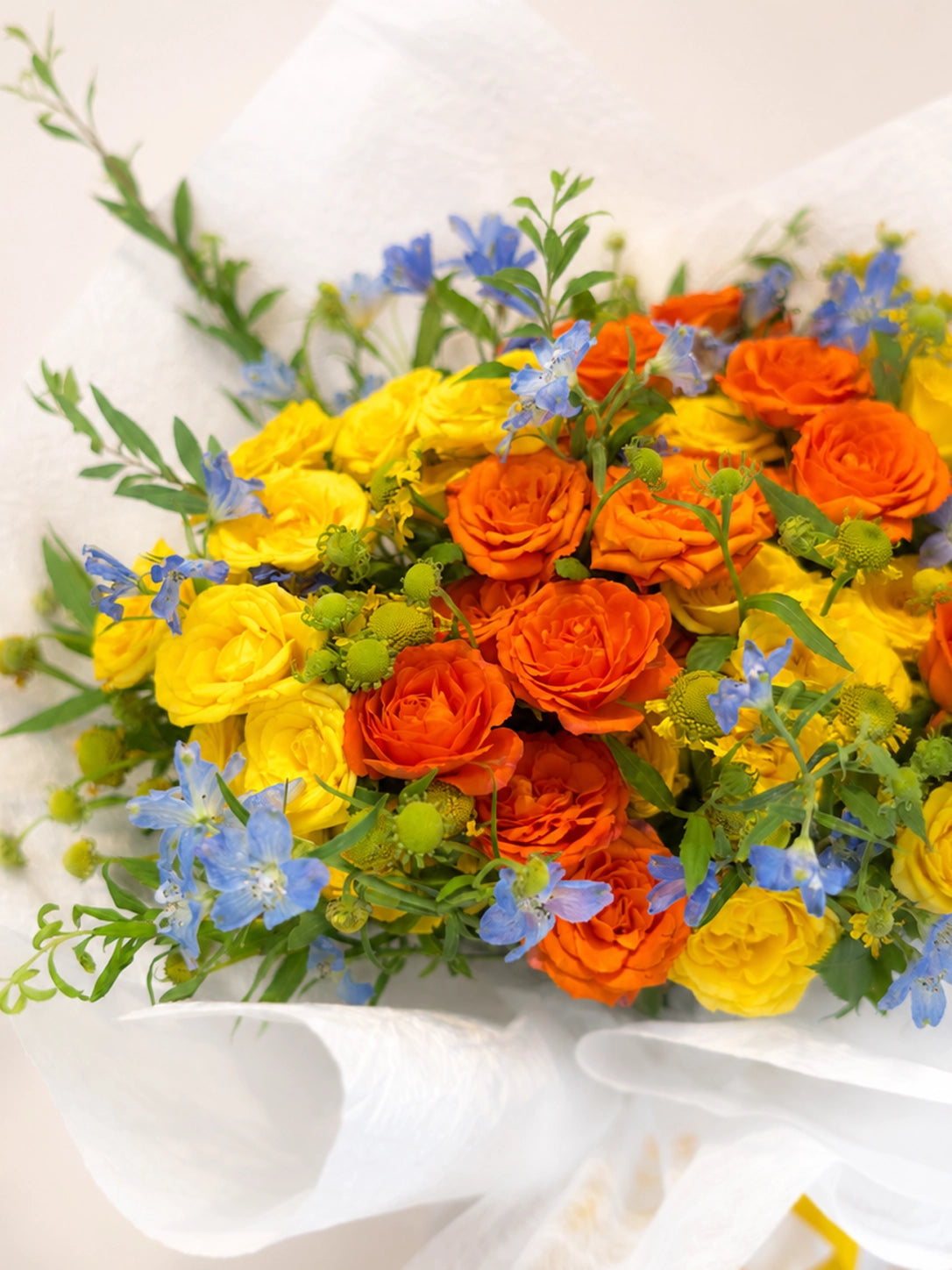 For You, Always close-up，橙色玫瑰、黃色 blooms 同藍色小花細節，vibrant floral arrangement full of warmth and optimism.