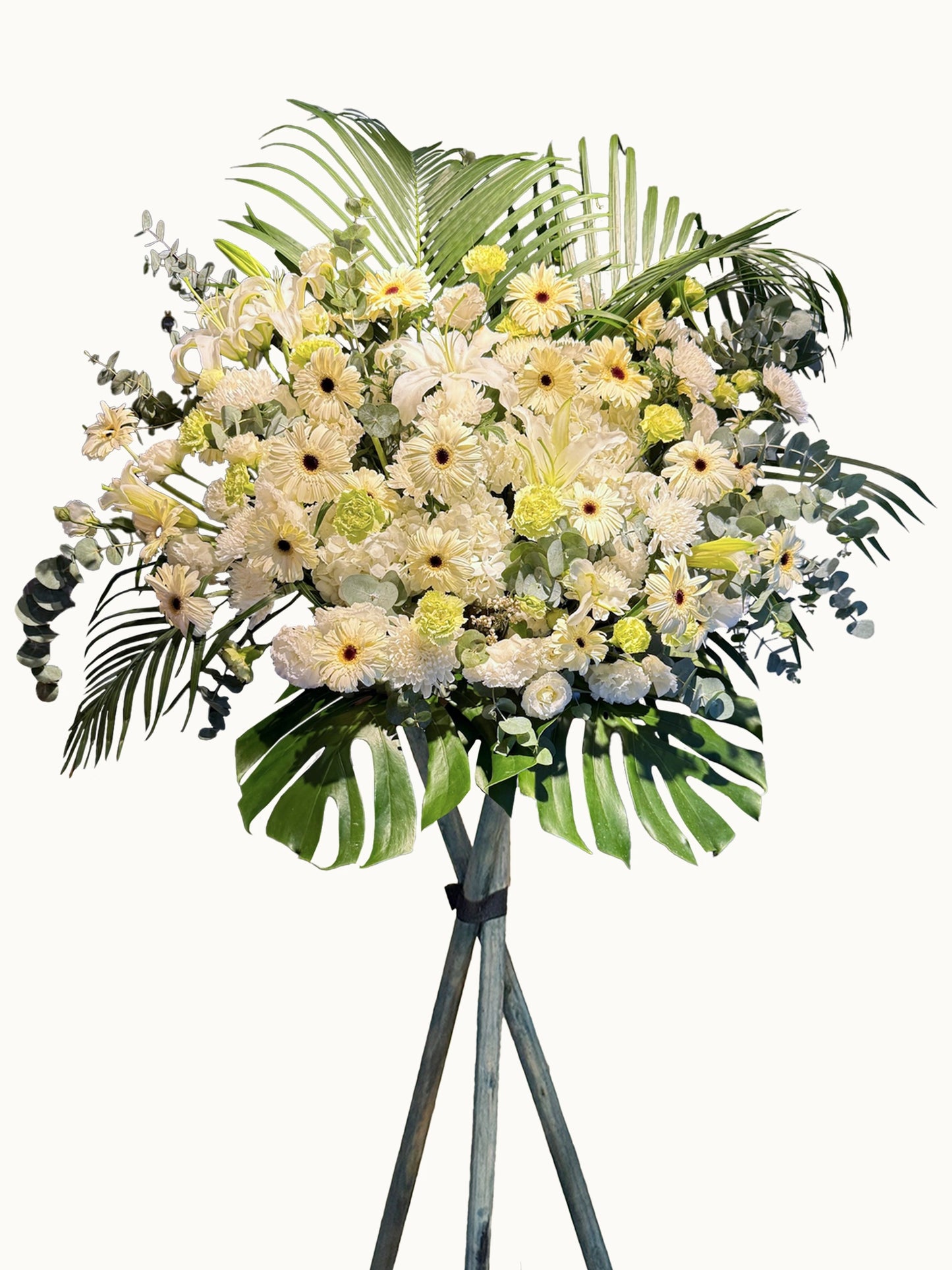 Ivory white 及 pale yellow blooms 配 tropical palm leaves 的大型 floral stand，可用於 sympathy 或 opening occasions