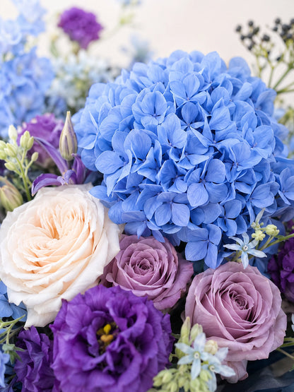 Midnight Embrace close-up，展示藍色繡球、紫色 lisianthus、裸粉玫瑰及白玫瑰細節