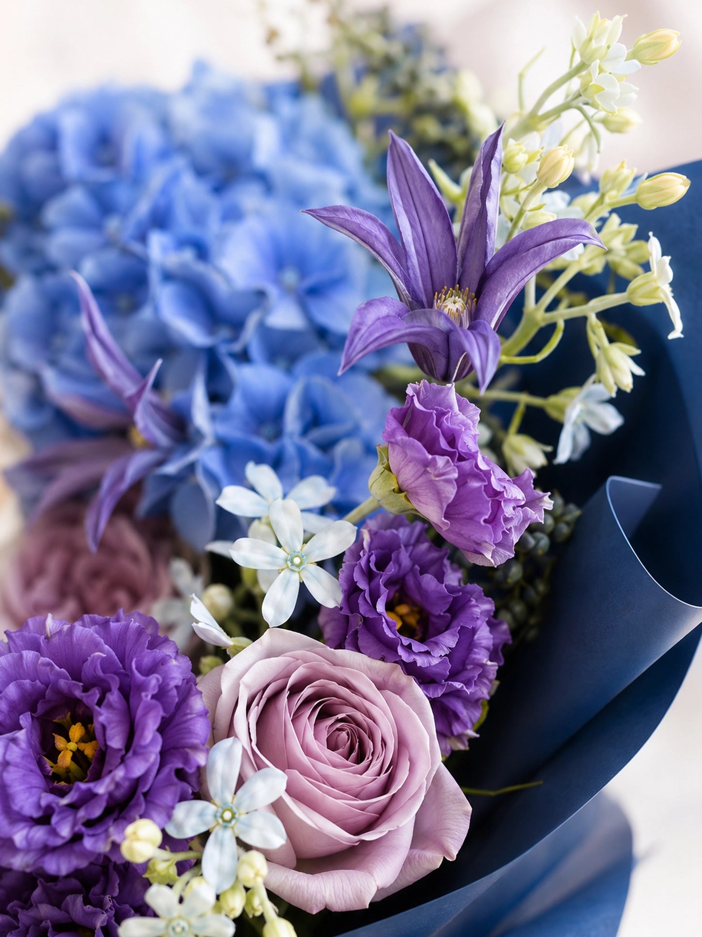 Nocturne Embrace close-up，展示 blue hydrangea、purple clematis、mauve rose 及深藍包裝
