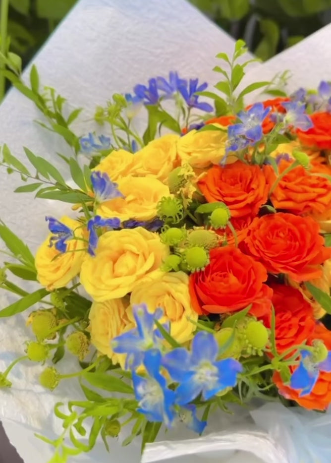 Where Light Begins bouquet 360° video，多角度展示橙色玫瑰、金黃色花材及藍色季節花，bright floral arrangement inspired by hope, light and beautiful new chapters.