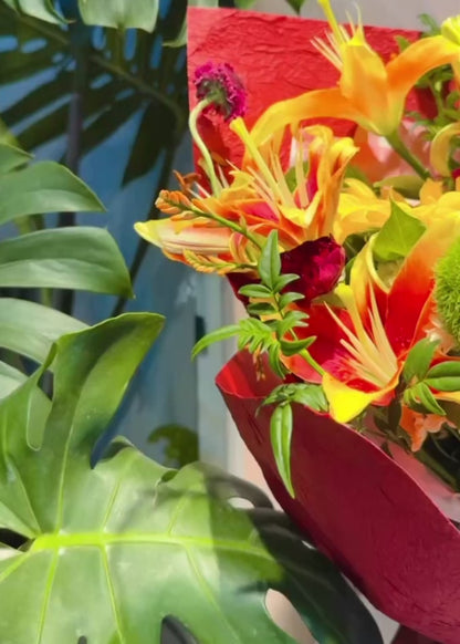 Amber Flame bouquet 360° video，展示鮮橙 lilies、雞冠花及酒紅包裝，多角度欣賞 vibrant floral arrangement inspired by golden sunsets.