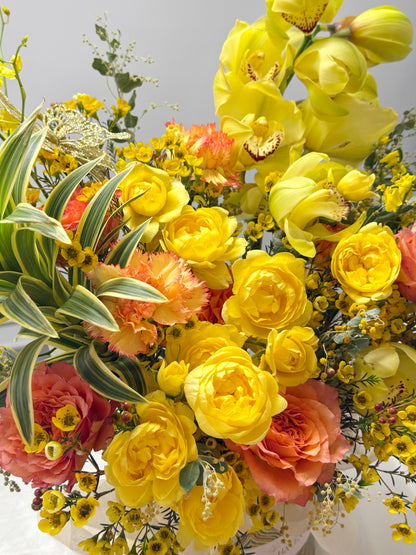 Yellow orchids、golden roses、orange accents 及 airy greenery 的 flower close-up